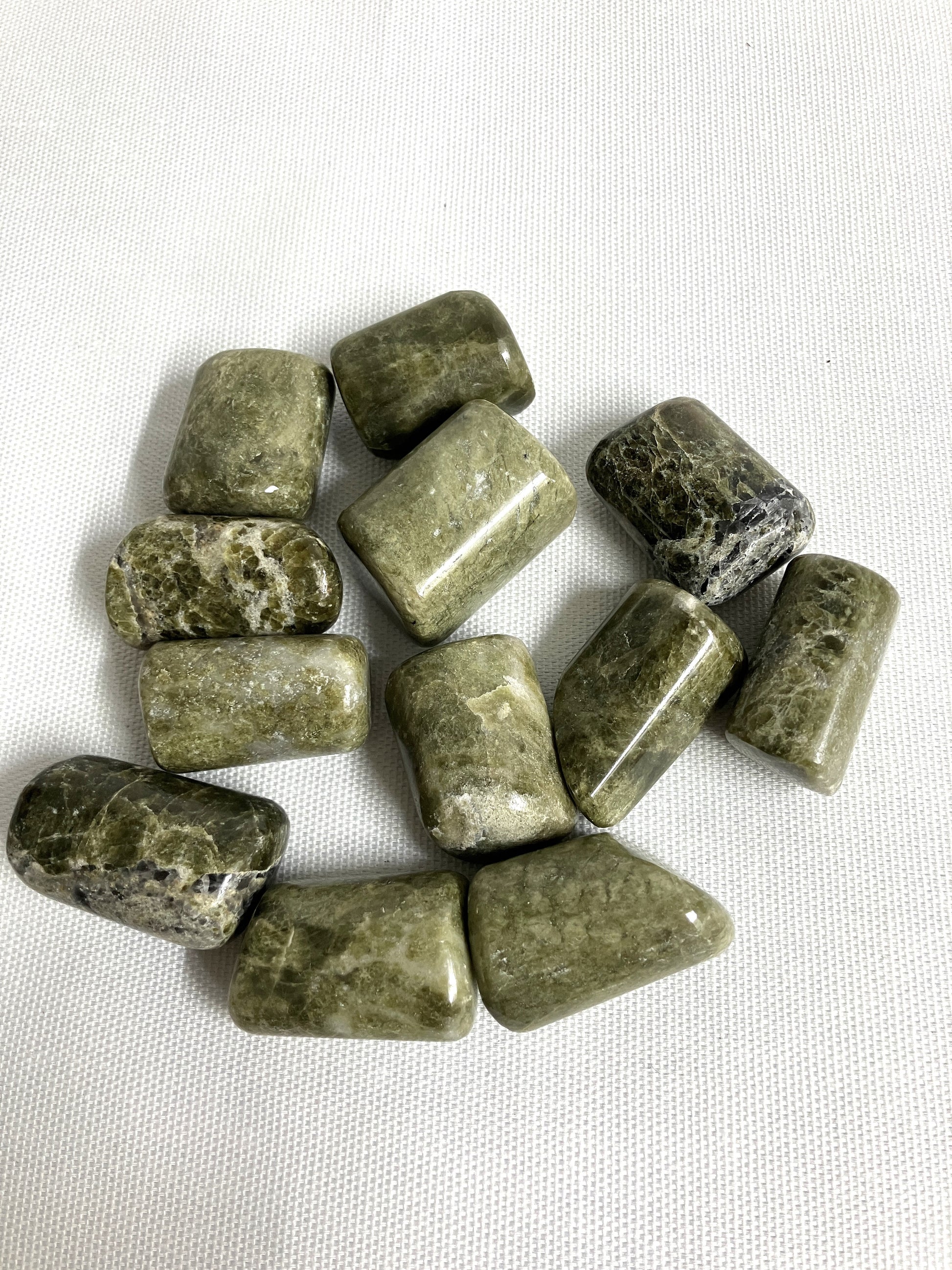 Closeup of Vesuvianite Tumbled Crystals on a white fabric background