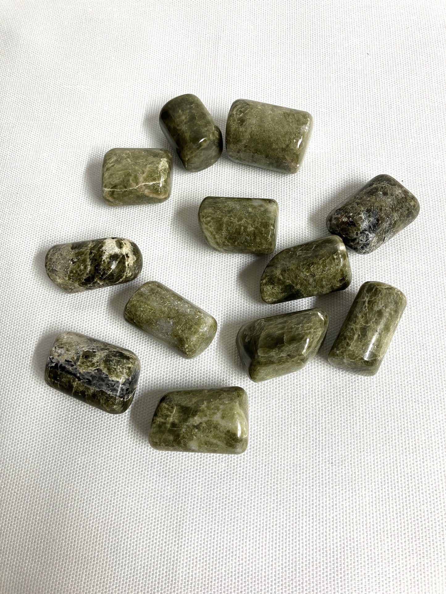 Back view of Vesuvianite Tumbled Crystals on a white fabric background