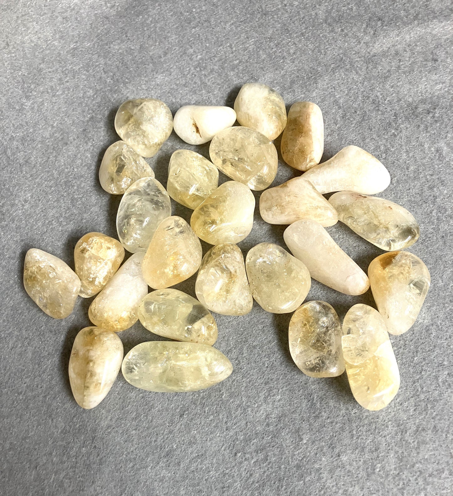 Collection of Citrine Tumbled Crystals showing assorted shaped and sizes on a gray surface