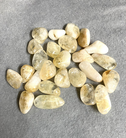 Collection of Citrine Tumbled Crystals showing assorted shaped and sizes on a gray surface