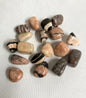 Group of Pink Zebra Jasper Crystals, variously shaped and colored placed on a light fabric background