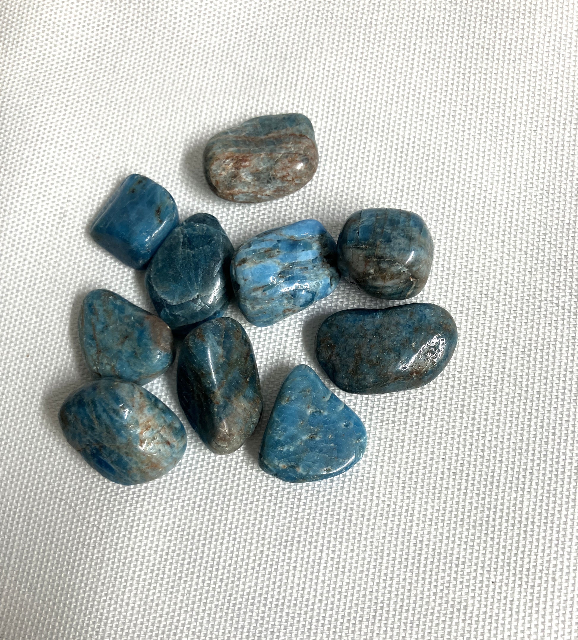 Group of Blue Apatite Crystals showing the pattern and colors  on a textured white surface
