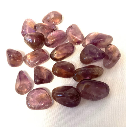 View of Ametrine Tumbled  Crystals under bright light on a white fabric background