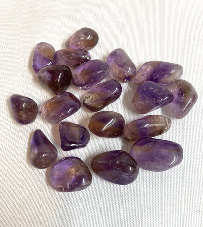 Top view of Ametrine Tumbled  Crystals on a white fabric background