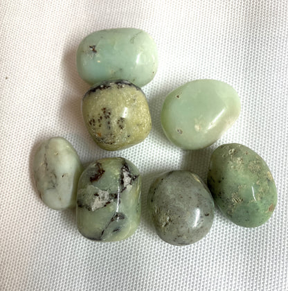Green Chrysoprase Crystals Showing the unique pattern of many stones shown on a textured white surface