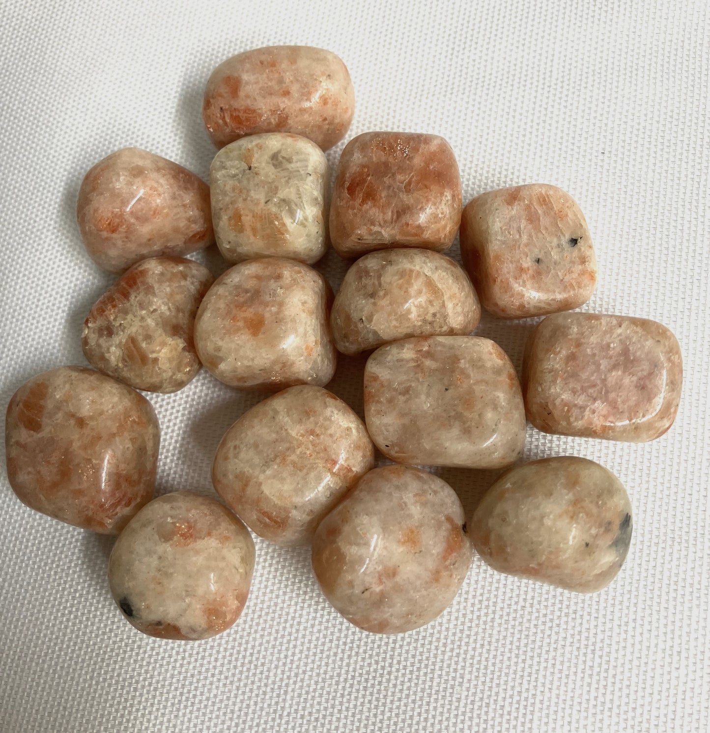 Tumbled Sun Stone Crystals on a white fabric background