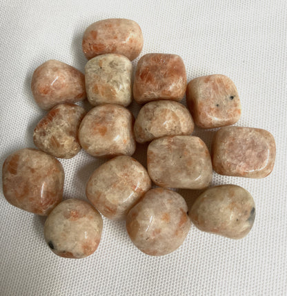 Tumbled Sun Stone Crystals on a white fabric background