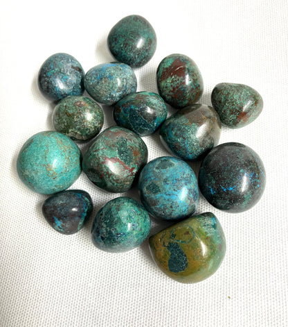 Back side of Chrysocolla Crystals showing the patterns and colors displayed on a white fabric backgroundl