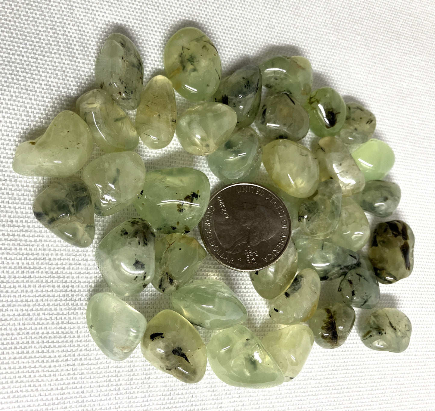 Prehnite with Epidote Crystals shown with a coin for scale on a white background