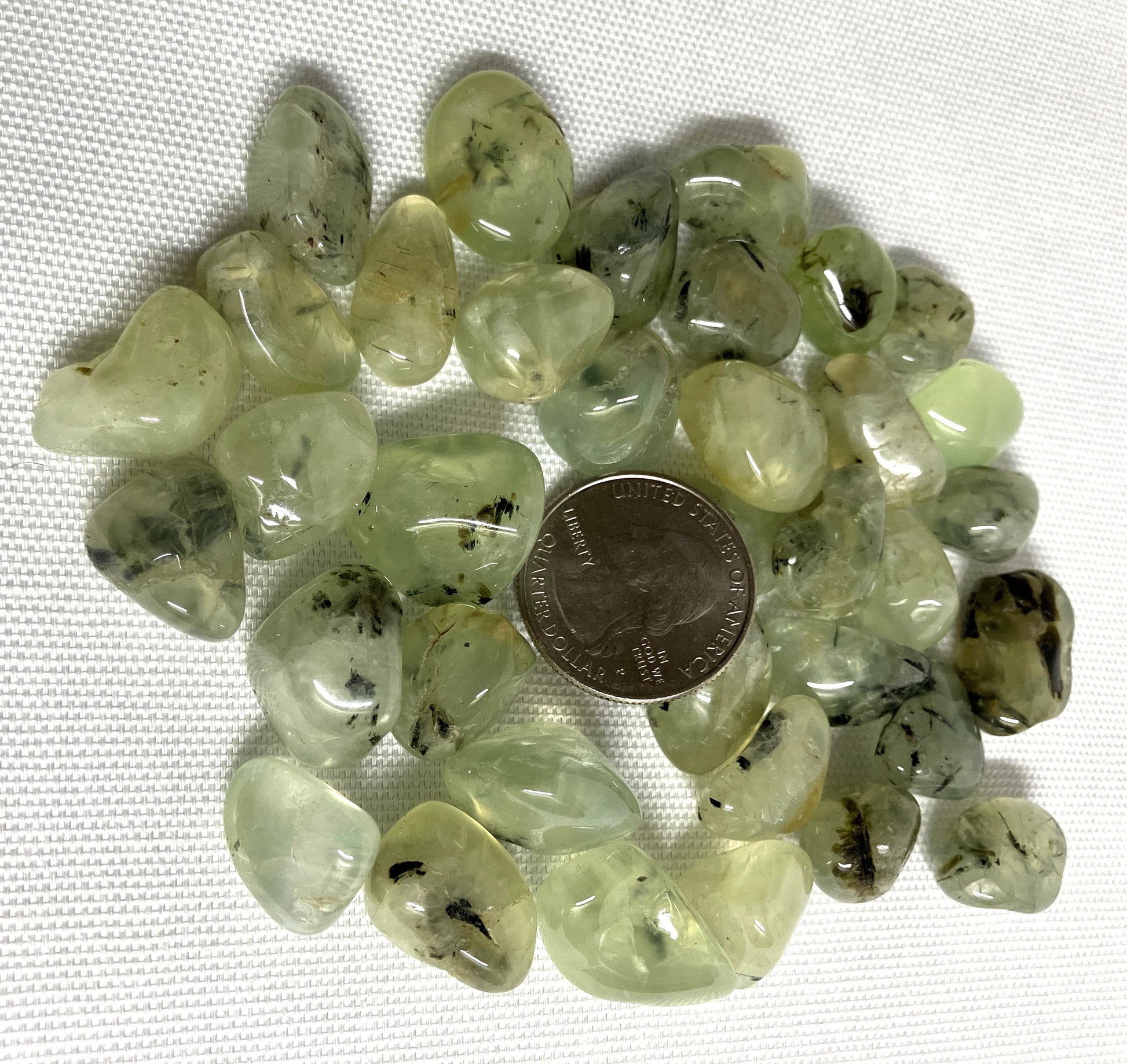 Prehnite with Epidote Crystals shown with a coin for scale on a white background