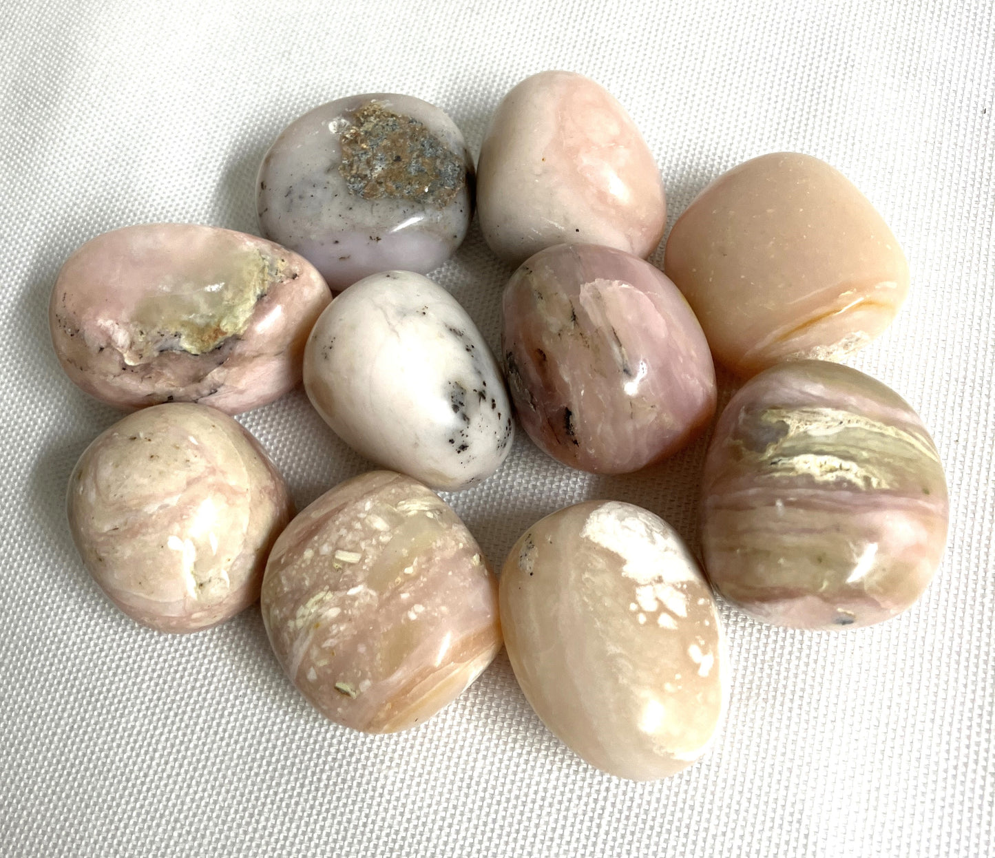 Pink Opal Crystals showing different colors on a white fabric background