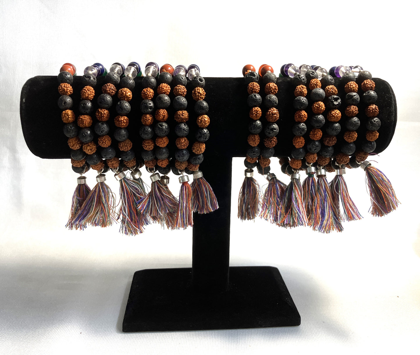 Chakra Stone Stretch Bracelet w/ Lava and Rudraksha Seeds on a black stand against a white background