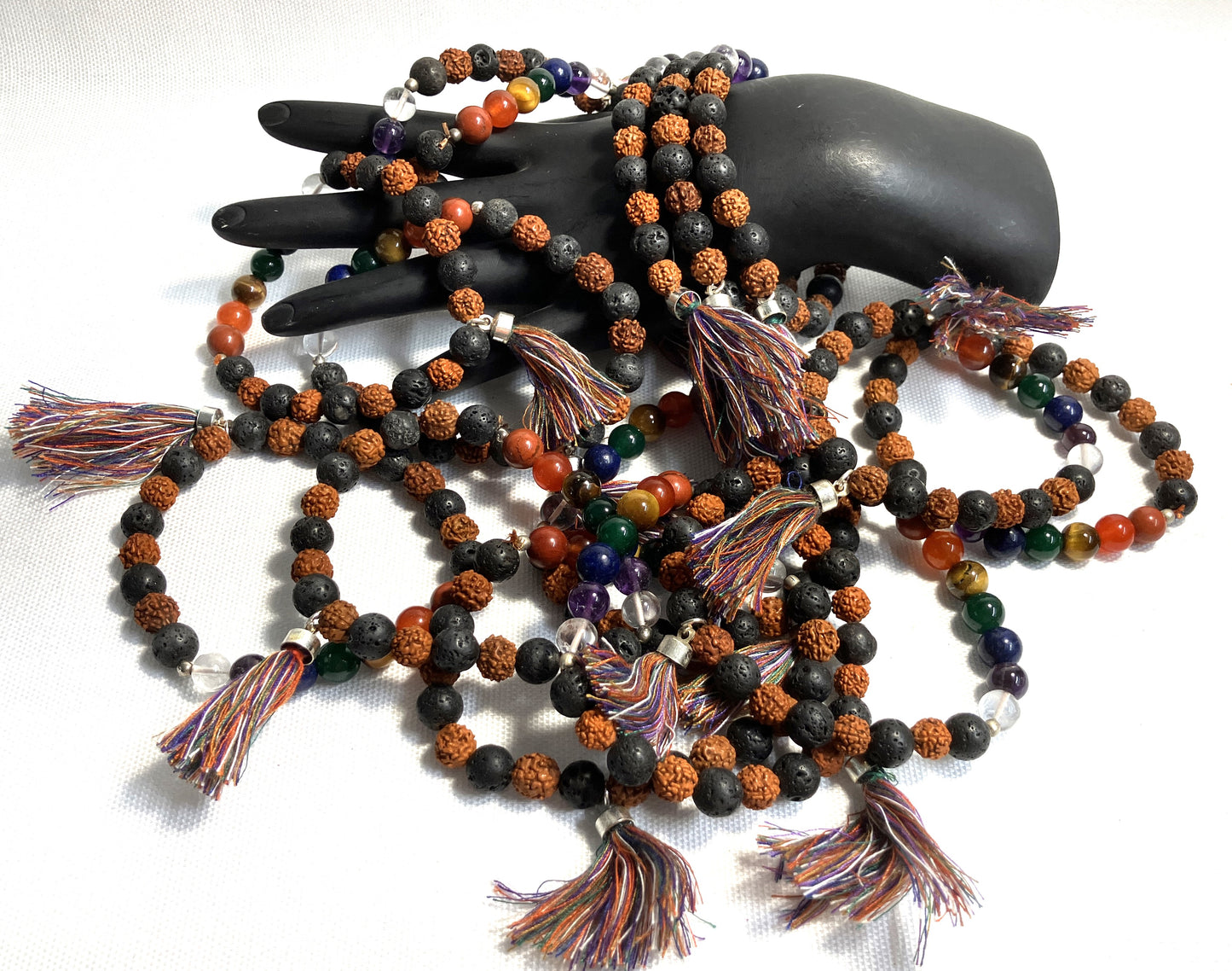 Chakra Stone Stretch Bracelet w/ Lava and Rudraksha Seeds with tassels on a black mannequin hand against a white background