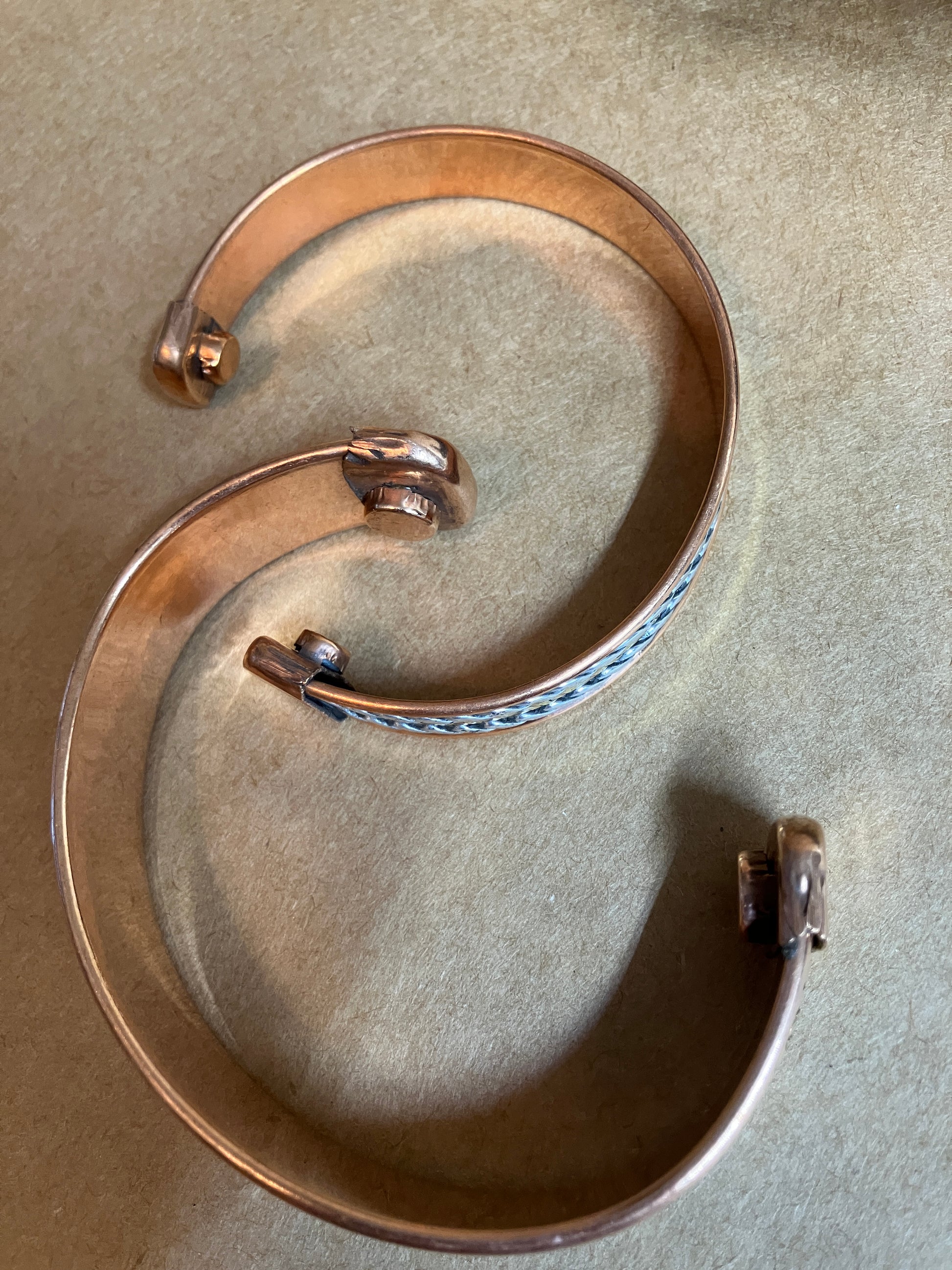 Copper bracelet showing the inside and placement of the magnets on a beige background