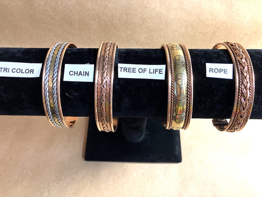 Four Copper Magnetic bracelets on a black stand with labels indicating 'Tri Color', 'Chain', 'Tree of Life', and 'Rope'.