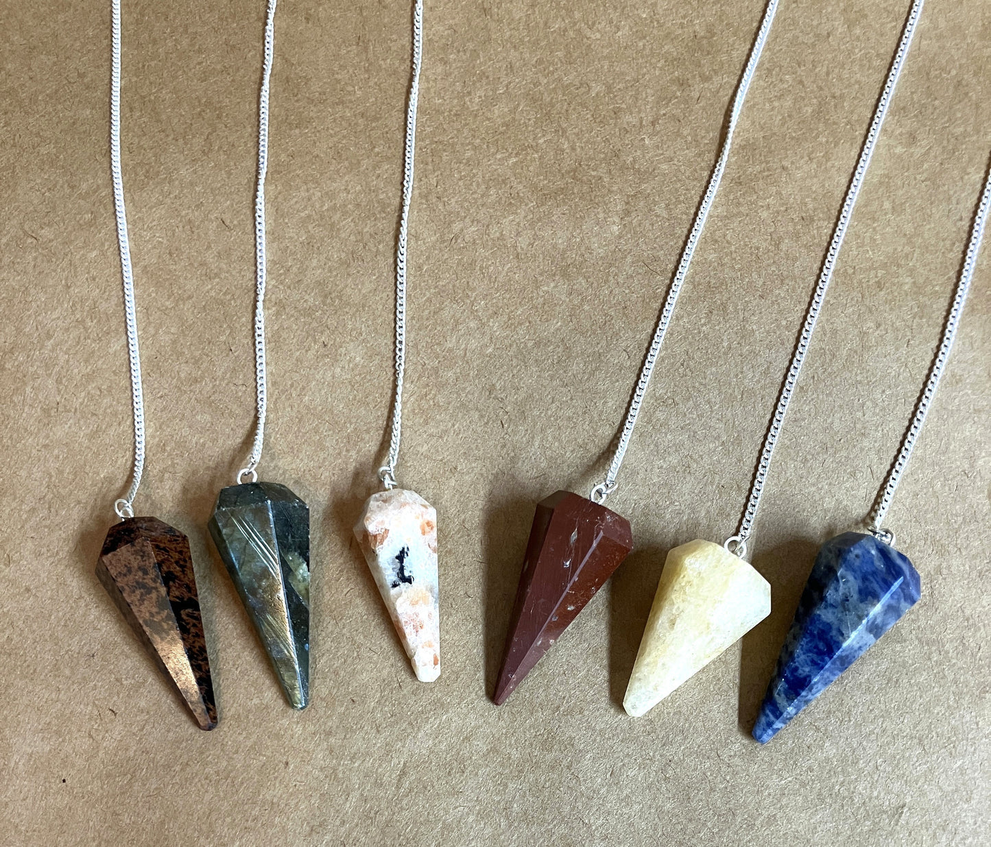 Six stone pendants on chains against a brown background