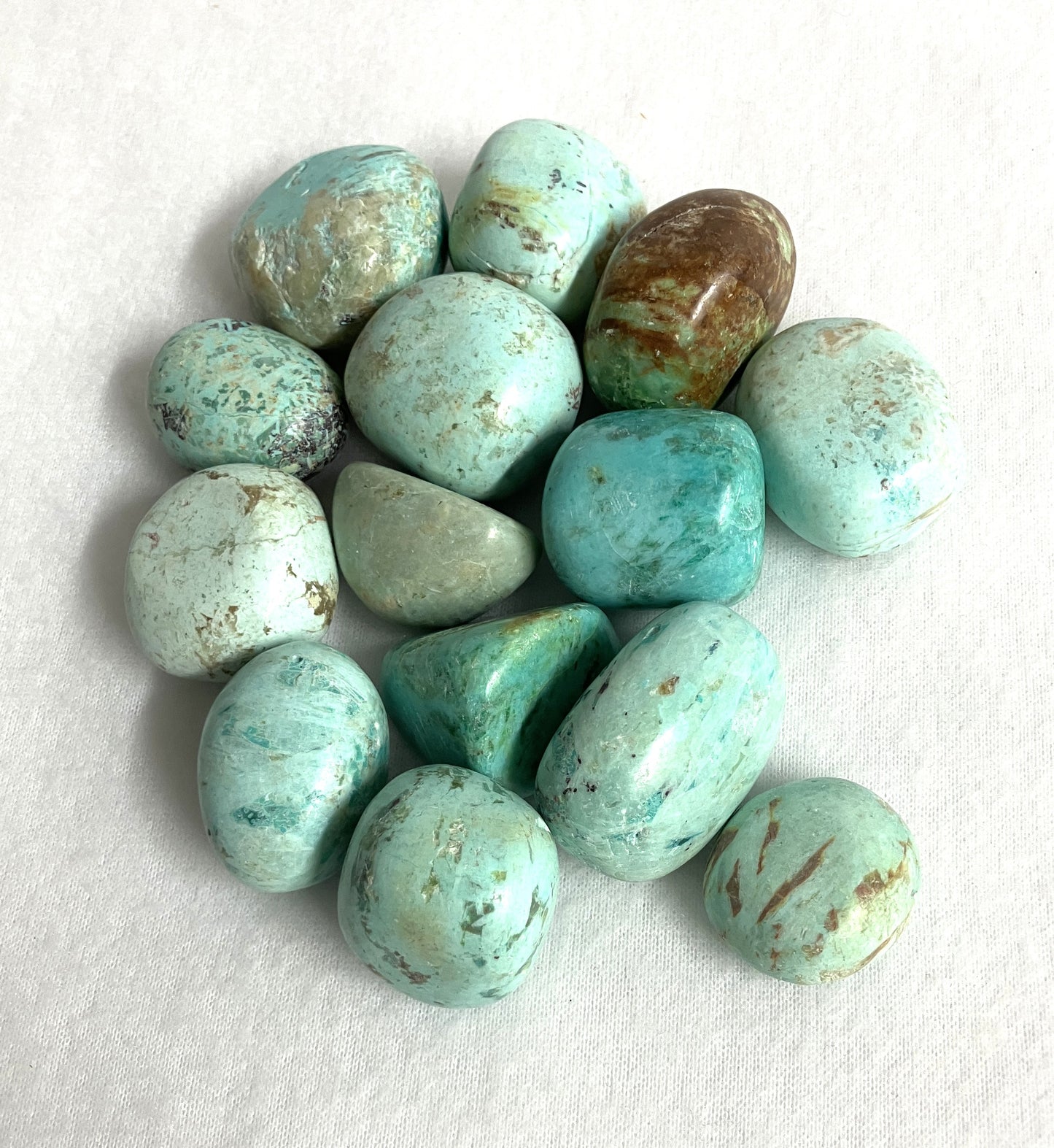 Closeup of Turquoise Tumbled Crystals from Peru on a white background