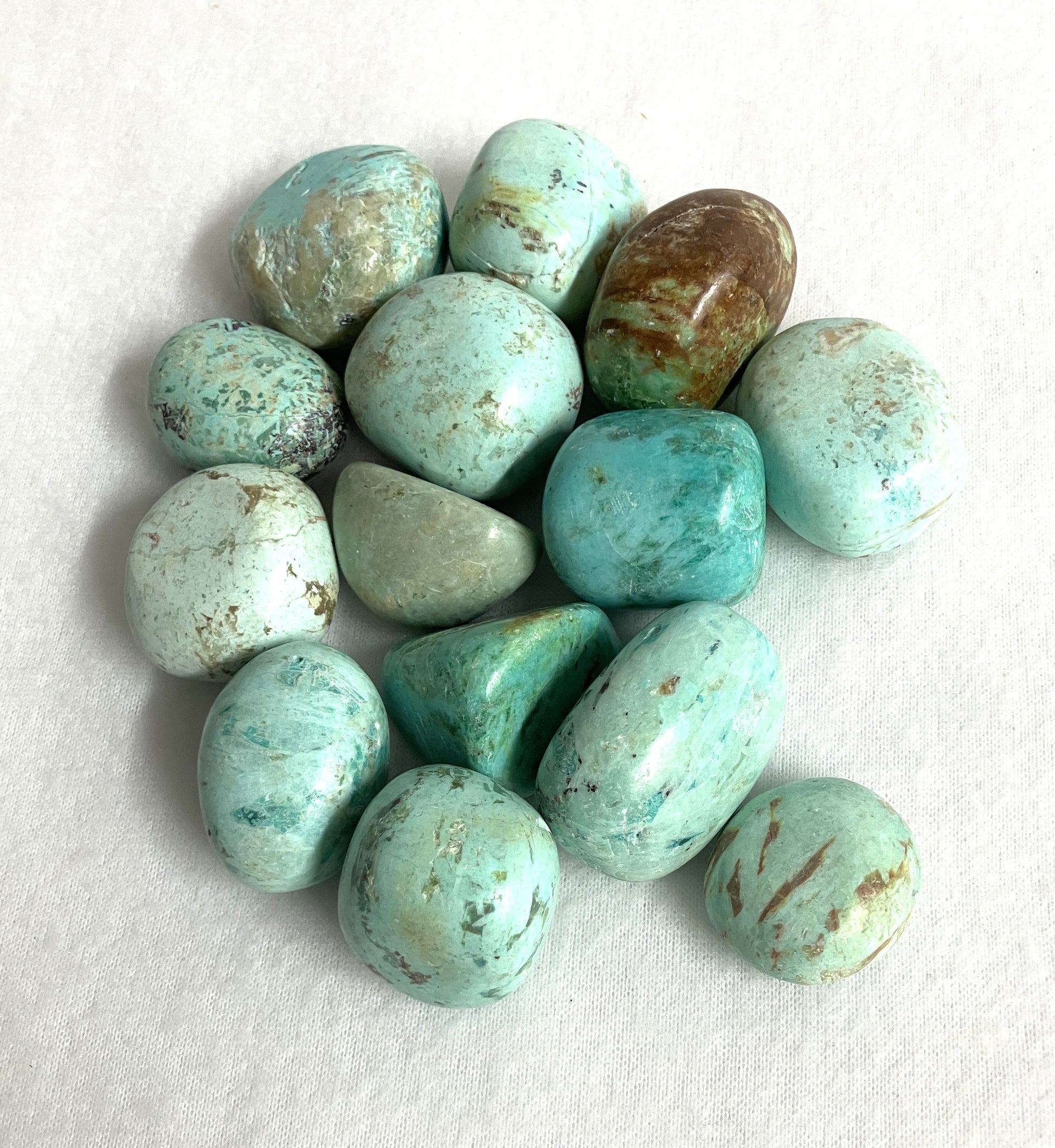 Closeup of Turquoise Tumbled Crystals from Peru on a white background