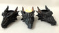 Three dragon head candle holders with a lit candle in the center on a white background